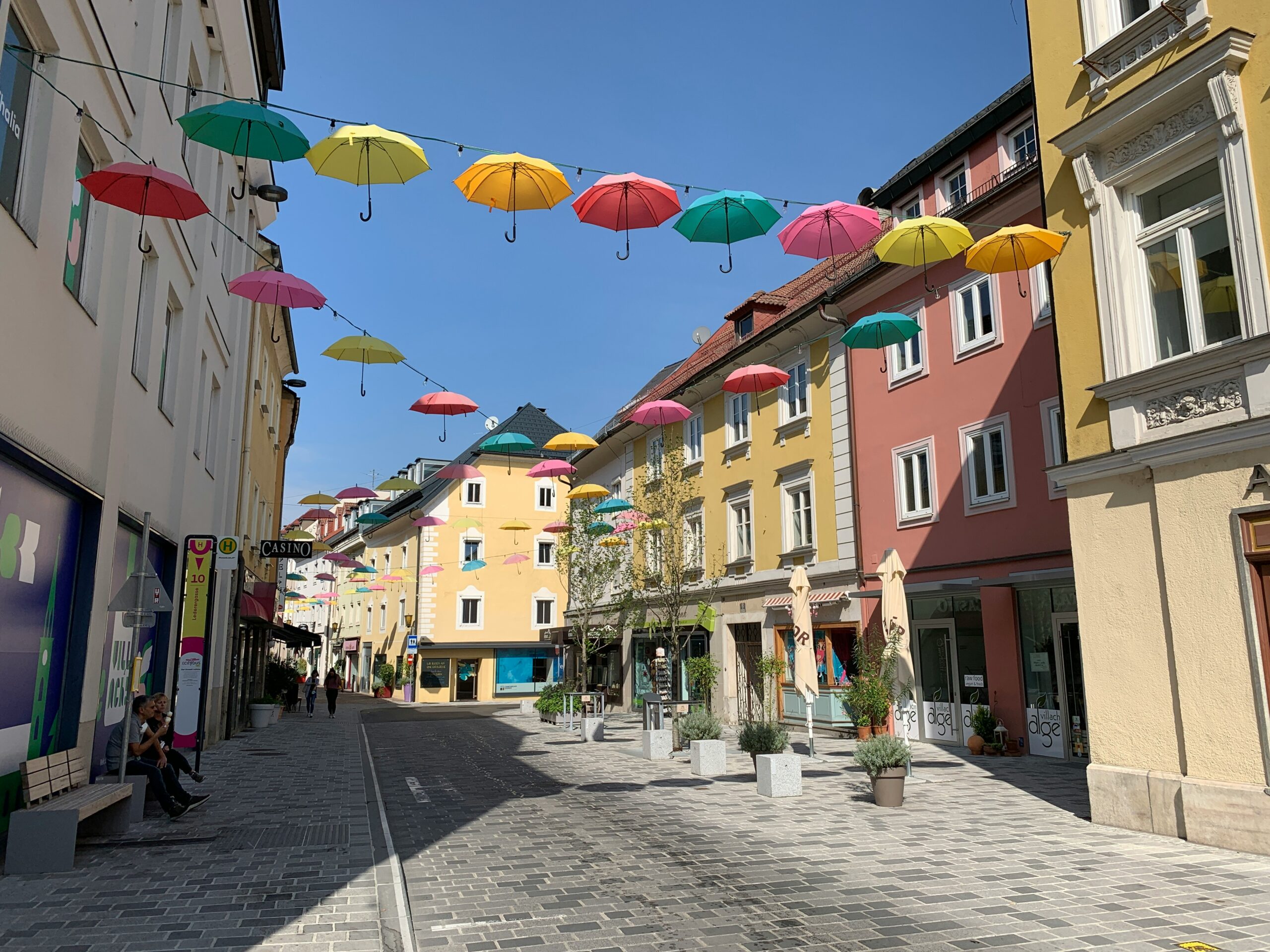 Eine mit herabhängenden bunten Schirmen geschmückte Gasse in der Villacher Innenstadt